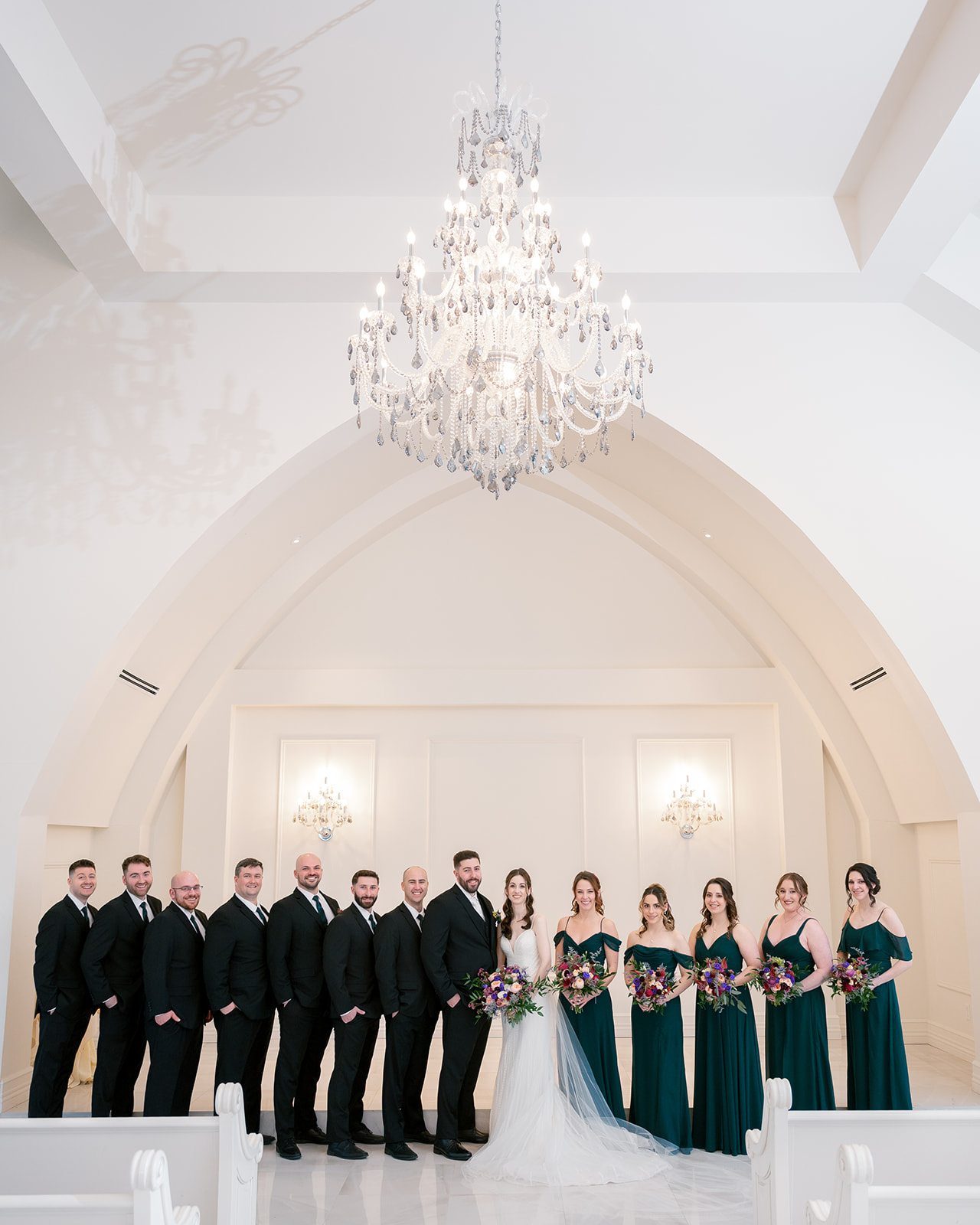 entire wedding party lined up next to the bride and groom in the aria chapel