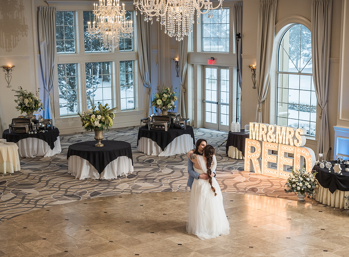 a bride and groom standing together in the aria ballroom
