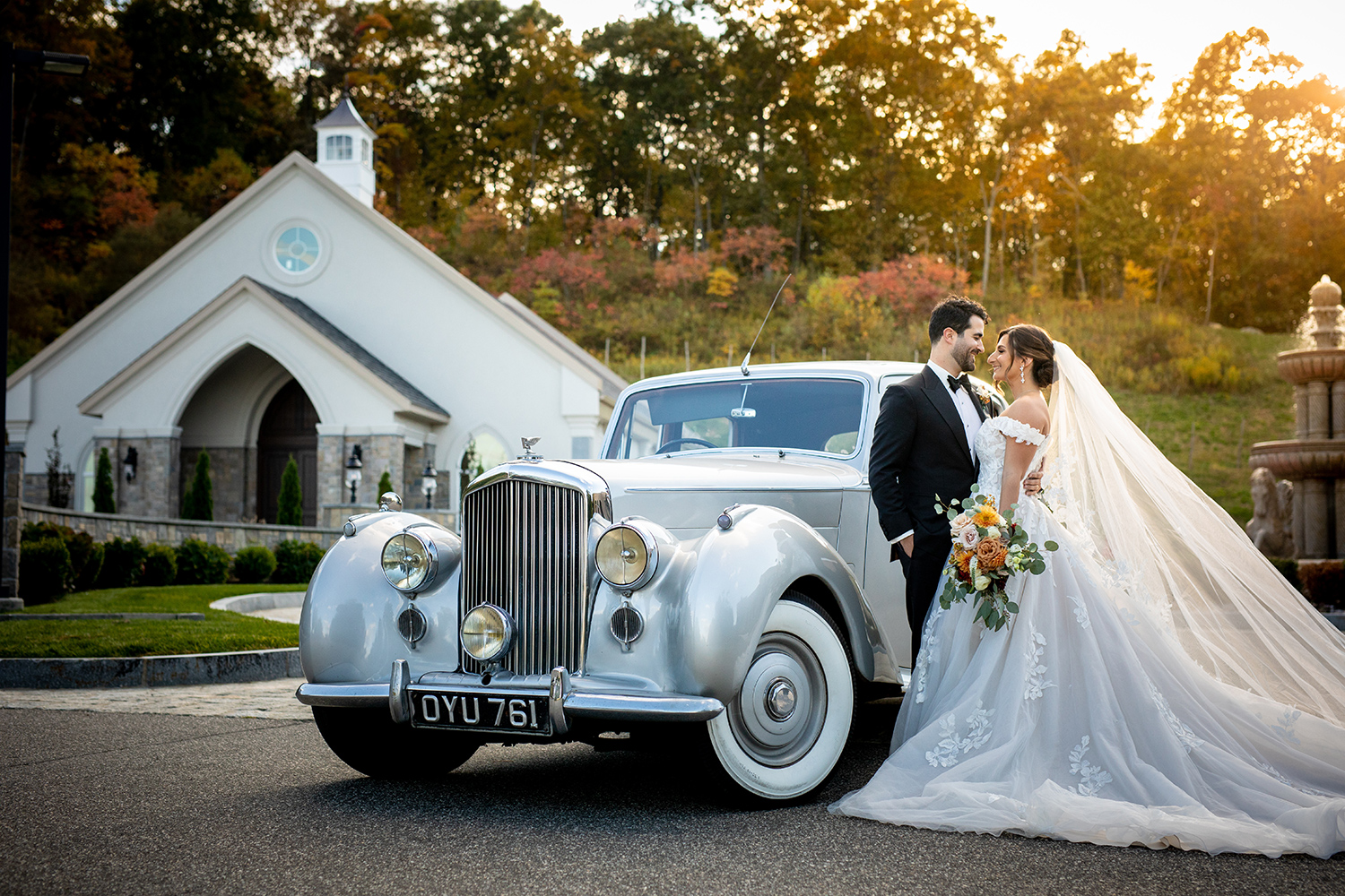 a bride and a groom standing next to a classic old car outside