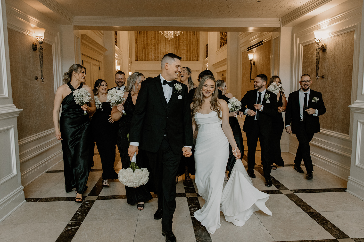 a bride and groom are walking towards the camera with the wedding party behind them