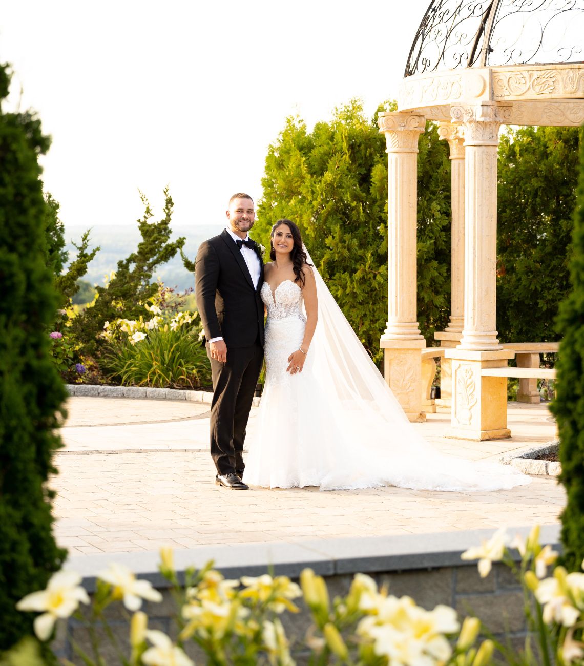 a bride and groom posing outside with the gazebo to their left