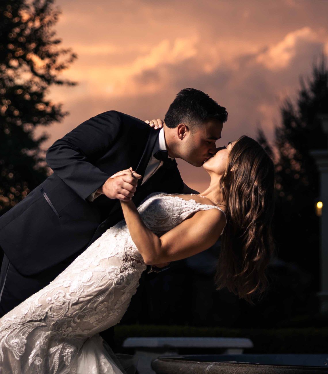 a bride and groom sharing a kiss outside with a beautiful sunset