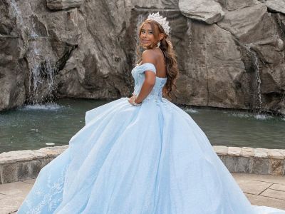 a teen girl posing in a light blue dress in front of a fountain