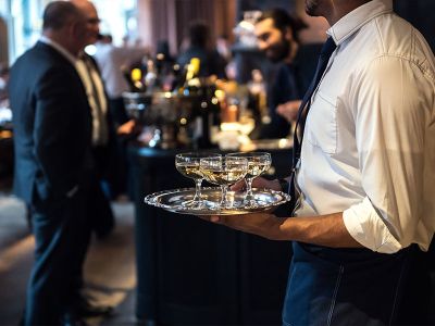 a waiter carrying cocktails on a silver platter