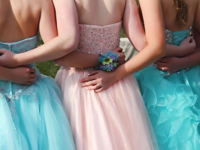 the backs of girls in prom dresses posing for a picture