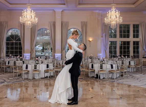 Couple dancing in the middle of an elegant ballroom on their wedding day.