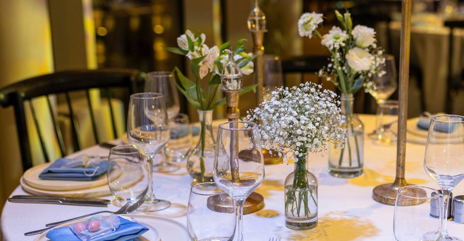 a table set for dinner with wine glasses and flowers